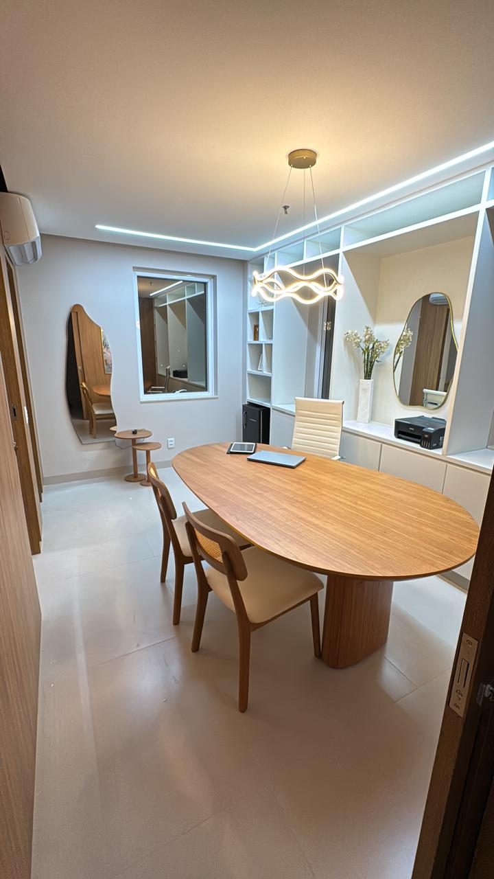 Consultório com estante branca, espelhos e mesa oval
