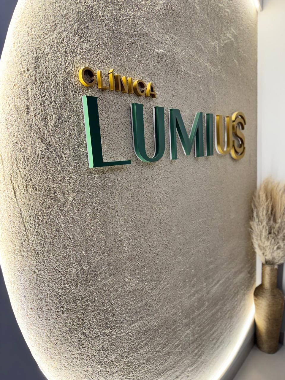 Parede da entrada com o letreiro Clínica Lumius em verde e dourado