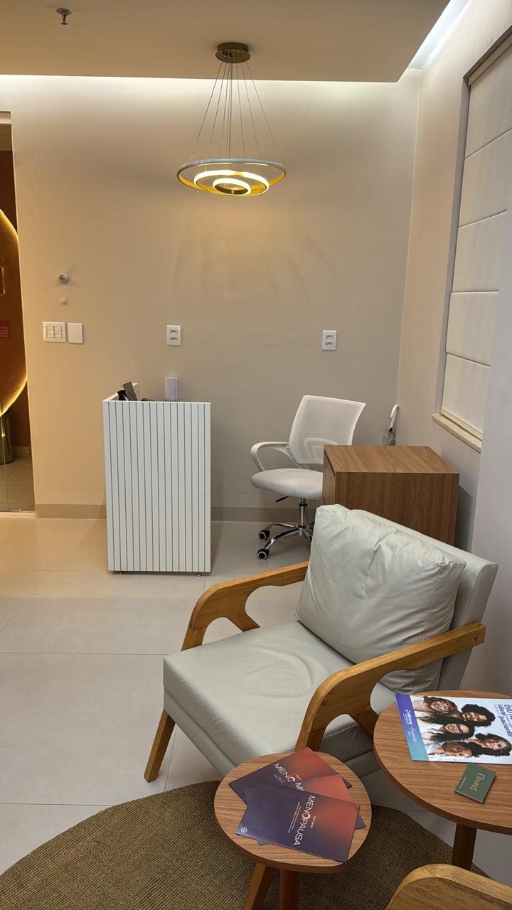 Recepção com poltrona, mesas de apoio e luminária circular