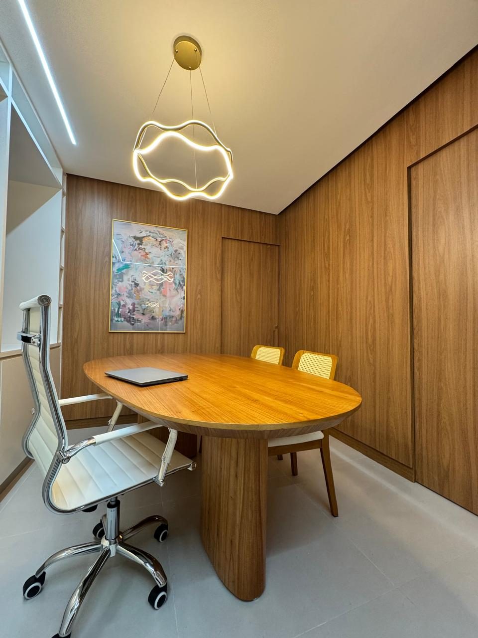 Sala de atendimento com painel de madeira e luminária dourada ondulada